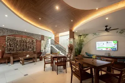 a restaurant with wooden ceilings and tables and chairs at Pepitu Dormitory By Sandat in Kuta