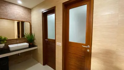 a bathroom with a wooden door and a sink at Pepitu Dormitory By Sandat in Kuta