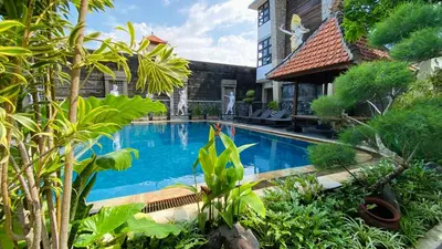 a swimming pool in front of a house with plants at Pepitu Dormitory By Sandat in Kuta