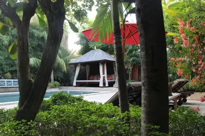 a gazebo with a red umbrella next to a pool at Villa Varuna in Legian