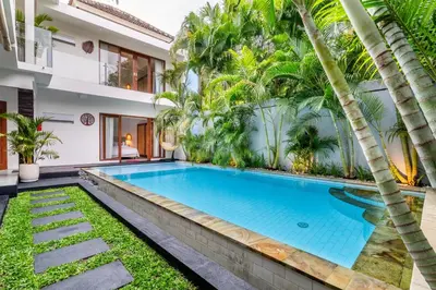 a swimming pool in the backyard of a house with palm trees at Villa Arbolita by JB Villas in Seminyak