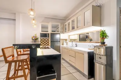 a kitchen with white cabinets and a black counter top at Villa Arbolita by JB Villas in Seminyak