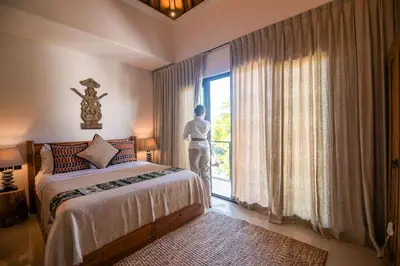 a man standing in a bedroom looking out the window at Sister Suites in Seminyak