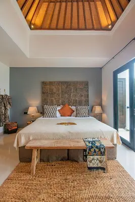 a bedroom with a large bed with a wooden headboard at Sister Suites in Seminyak