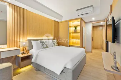 a bedroom with a white bed and a tv at Olaia by Kozystay - Nusa Dua in Nusa Dua