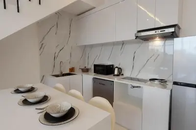 a white kitchen with a table and chairs and a counter at Cozy Seminyak Loft 360 in Seminyak