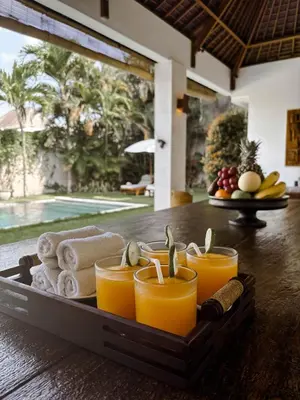 a tray of orange juice and towels on a table at Villa Chocolat Seminyak 2 Bedroom in Seminyak
