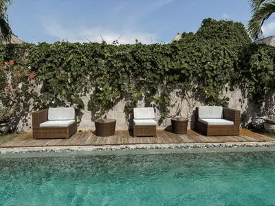 a group of chairs sitting on a deck next to a pool at Villa Chocolat Seminyak 2 Bedroom in Seminyak