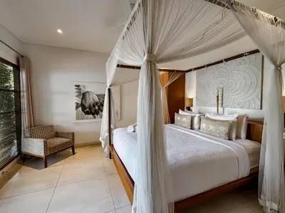 a bedroom with a canopy bed and a chair at Villa Chocolat Seminyak 2 Bedroom in Seminyak