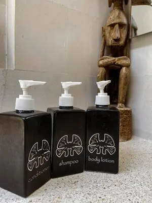 two bottles of body lotion sitting next to a statue at Villa Chocolat Seminyak 6 Bedroom in Seminyak