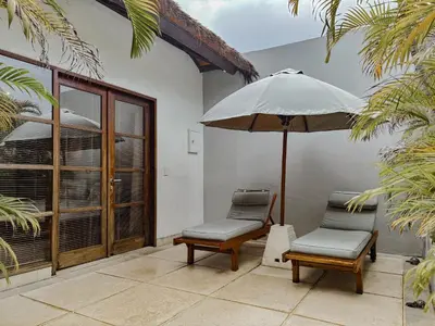 a pair of chairs and an umbrella on a patio at Villa Chocolat Seminyak 6 Bedroom in Seminyak
