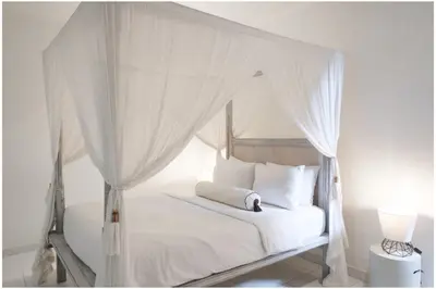 a white bed with a canopy with white pillows at Villa Hari in Seminyak