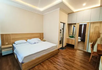 a bedroom with a large bed and a desk at Room Hangtuah Sanur in Kuta