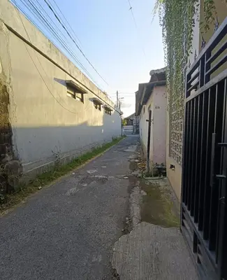 an empty alley with a fence and a building at Room Hangtuah Sanur in Kuta