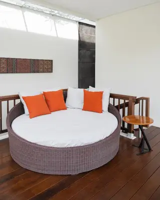 a bed with orange and white pillows in a room at The Mango Villa Jimbaran Jimbaran in Jimbaran