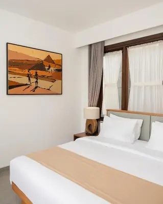 a bedroom with a bed and a painting on the wall at The Mango Villa Jimbaran Jimbaran in Jimbaran
