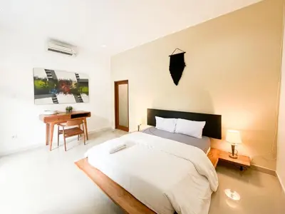 a bedroom with a large bed and a desk at Villa Sayang 2 in Seminyak