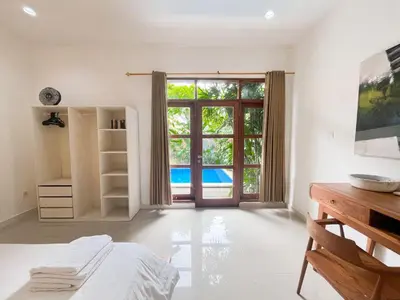 a bedroom with a bed and a large window at Villa Sayang 2 in Seminyak