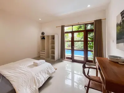a bedroom with a bed and a desk and a window at Villa Sayang 2 in Seminyak