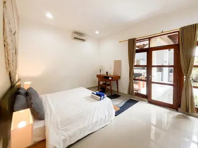 a bedroom with a bed and a table and a window at Villa Sayang 2 in Seminyak