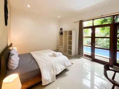 a bedroom with a bed and a large window at Villa Sayang 2 in Seminyak