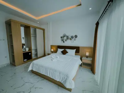 a bedroom with a large white bed and a mirror at Pachira Living Legian in Legian