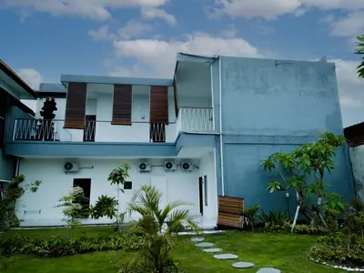 a blue and white house with a balcony at Pachira Living Legian in Legian