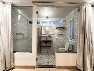a bathroom with a toilet and a shower door at House Jimbaran Kuta 3 bedroom 8 pax SukaBali 6 in Jimbaran