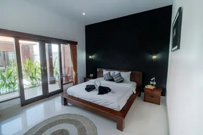a bedroom with a bed with a black wall at Villa Moza in Canggu