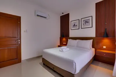 a bedroom with a large white bed with a wooden headboard at Villa Taman Seminyak 44 near Double Six Beach in Seminyak