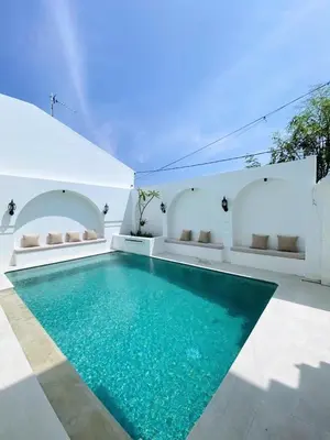 a pool in a house with blue water at Ara Santvana Villa Bali in Legian