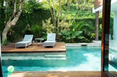 two chairs sitting on a wooden deck next to a swimming pool at Villa Sassy - Stunning Private Award Winning Seminyak Oasis in Seminyak