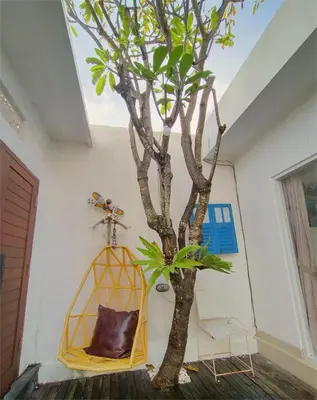 a tree in a room with a chair next to it at Bluna Villa seminyak in Seminyak