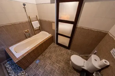 a bathroom with a toilet and a bath tub at The Mupu Villa Seminyak in Seminyak