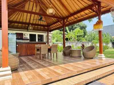 an outdoor kitchen and dining area with a wooden pergola at UCU VILLAGE at ULUWATU JIMBARAN in Jimbaran