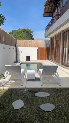 two lounge chairs and a pool in a yard at Wakajima House kuta Utara in Kerobokan
