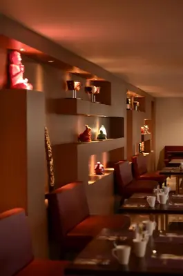 a dining room with tables and chairs and lights at Quest San Denpasar by ASTON in Denpasar