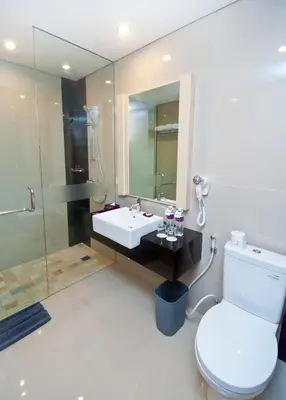 a bathroom with a sink and a toilet and a mirror at Quest San Denpasar by ASTON in Denpasar
