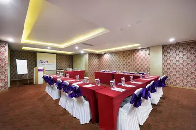 a banquet hall with red and white tables and blue bows at Quest San Denpasar by ASTON in Denpasar