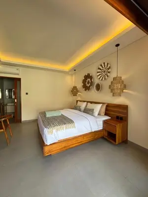 a bedroom with a large bed and a table at Villa Taoro Jimbaran in Jimbaran