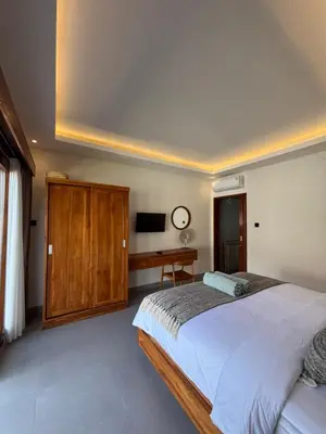 a bedroom with a large bed and a desk at Villa Taoro Jimbaran in Jimbaran