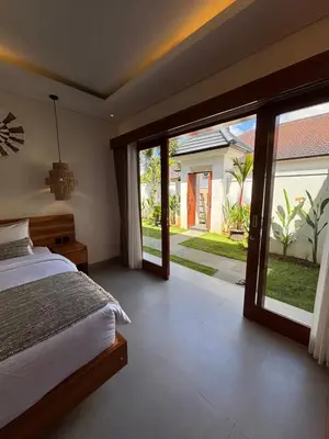 a bedroom with a bed and sliding glass doors at Villa Taoro Jimbaran in Jimbaran