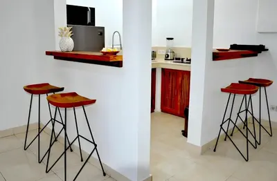 a kitchen with three red bar stools in front of a counter at Villa Kangaroo Seminyak next to double six beach in Seminyak