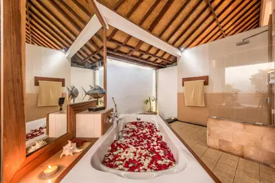 a bath tub filled with red flowers in a room at Villa Panda Seminyak next to KU DE TA Beach Club in Seminyak