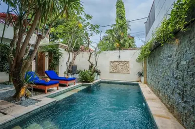 a pool in a backyard with blue chairs and trees at Villa Orange 2BR Seminyak by Exotic Bali Properties in Badung