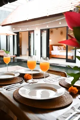a table with two glasses of orange juice on it at Villa O'Anne II in Seminyak