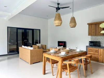 a kitchen and living room with a wooden table and chairs at Luxe 2Bedrooms D Villa Berawa - Near Beach,FINNS & ATLAS in Canggu