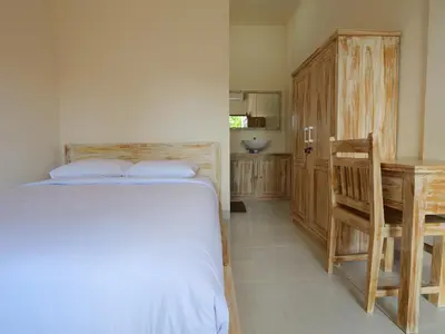 a bedroom with a bed and a desk and a table at Ken Ken Guest House in Seminyak