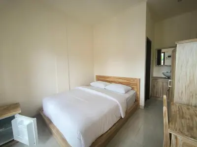 a bedroom with a large bed with white sheets at Ken Ken Guest House in Seminyak