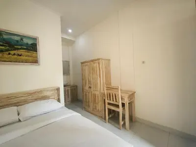 a bedroom with a bed and a wooden chair at Ken Ken Guest House in Seminyak
